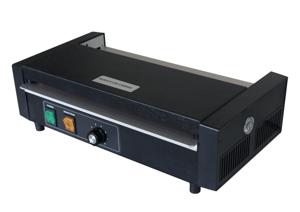 Side-angled view of a heavy-duty 12-inch black pouch laminator. The front panel features a green power switch, an orange ready light, a numerical dial knob, and a metal feed tray labeled 'Always Use Carrier'.